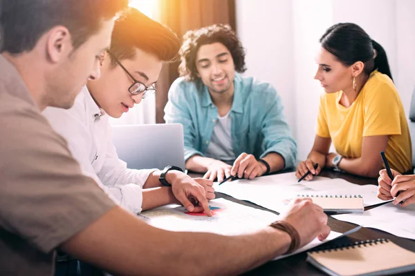 Grupo multicultural de colegas de negocios que discuten en la mesa con gráficos en la oficina moderna - foto de stock