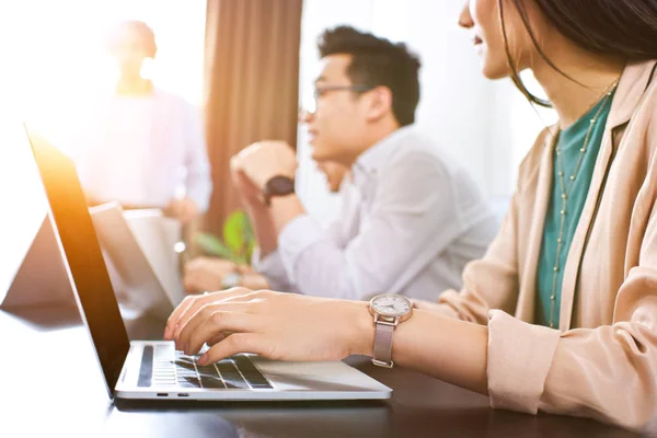 Cropped shot of businesswoman typing on laptop while her colleagues having discussion at modern office — Stock Photo