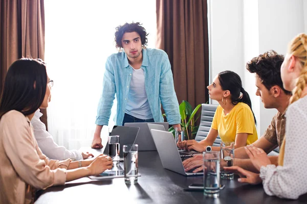 Parceiros de negócios multiculturais que têm reunião à mesa com laptops no escritório moderno — Fotografia de Stock