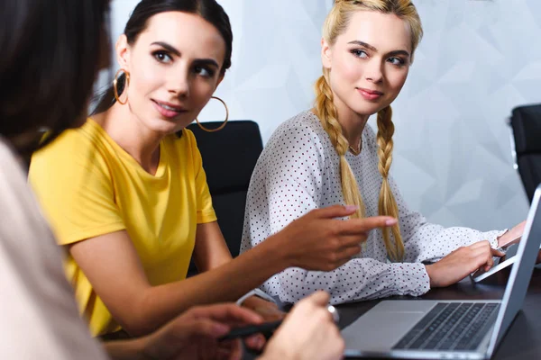 Mujer de negocios señalando con el dedo en la pantalla del ordenador portátil a colega en la oficina moderna - foto de stock