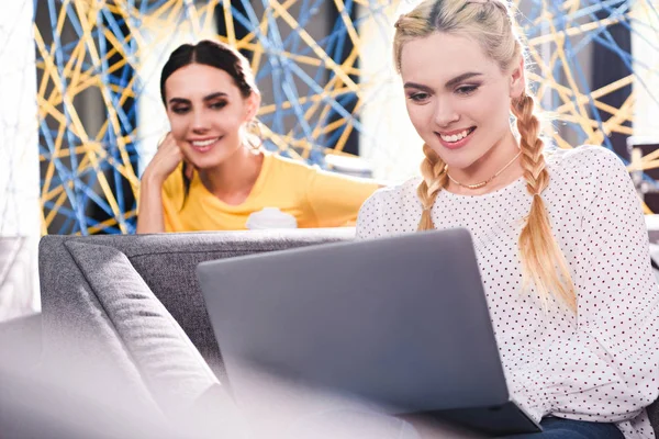 Deux femmes d'affaires souriantes utilisant un ordinateur portable au bureau de coworking moderne — Photo de stock