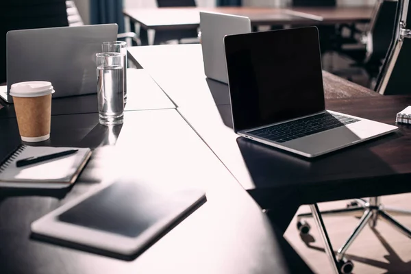 Close up view of digital tablet, laptops, textbook, paper cup of coffee on table at modern office — Stock Photo