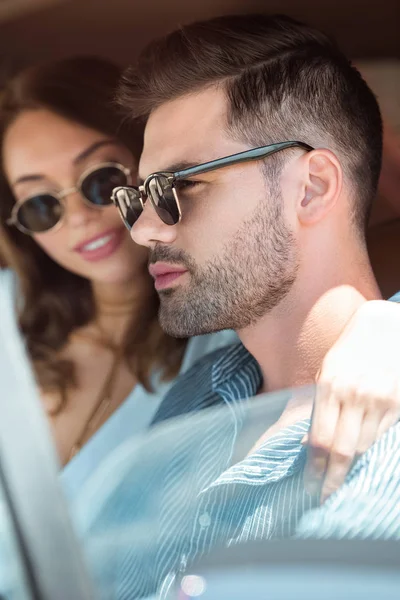 Beau jeune couple en lunettes de soleil voiture de conduite — Photo de stock