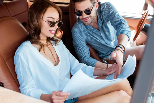 Belo casal olhando para o mapa no carro durante a viagem de carro — Fotografia de Stock