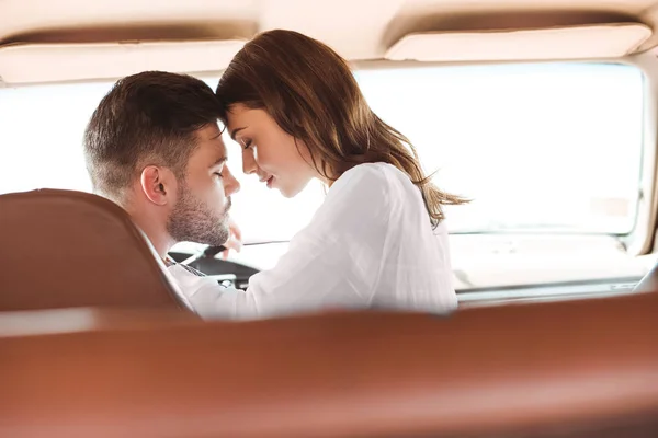 Hermosa pareja con los ojos cerrados va a besar en el coche juntos - foto de stock
