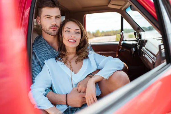 Felice giovane coppia di viaggiatori abbracciati e seduti in auto — Foto stock