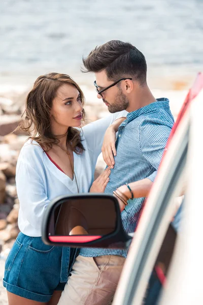 Hermosa feliz pareja abrazando cerca de coche juntos - foto de stock