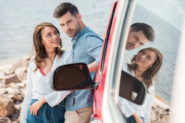 Junges Paar umarmt sich am Auto in Meeresnähe — Stockfoto