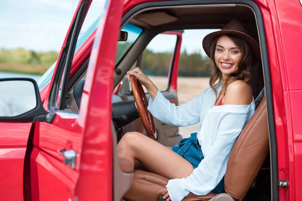 Attrayant conducteur féminin dans le chapeau assis dans la voiture pendant le voyage sur la route — Photo de stock