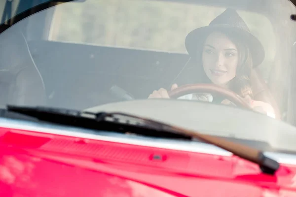 Schöne junge Frau mit Hut fährt Auto während Roadtrip — Stockfoto