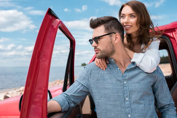 Beautiful couple of travelers standing near red car — Stock Photo