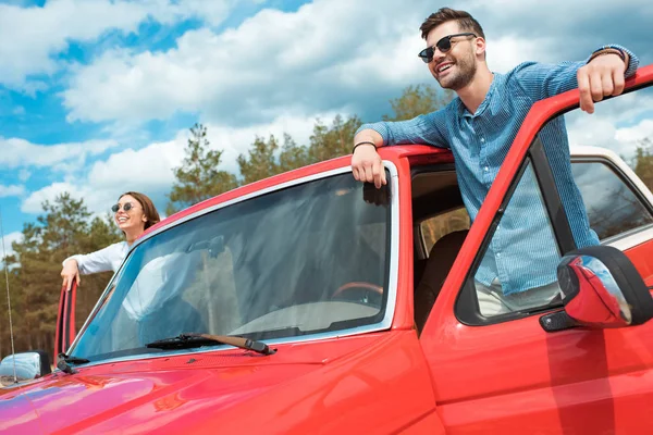 Feliz joven pareja de viajeros en rojo jeep - foto de stock