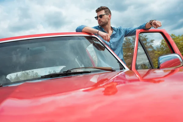 Viajero masculino con estilo de pie en el coche rojo - foto de stock