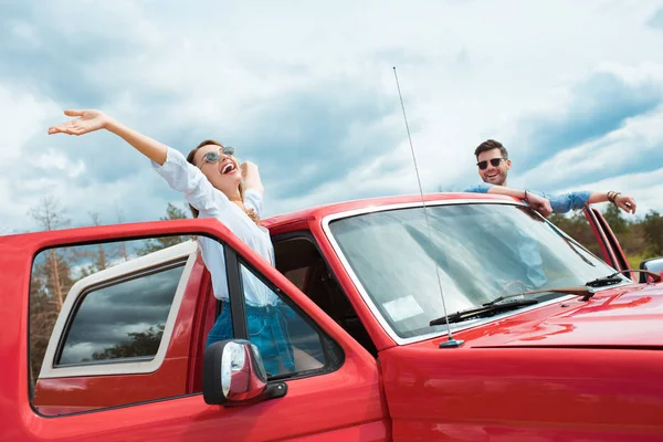 Alegre pareja de viajeros en rojo jeep - foto de stock