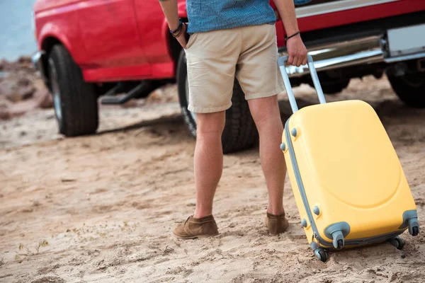 Cropped view of man with yellow travel bag going to car — Stock Photo