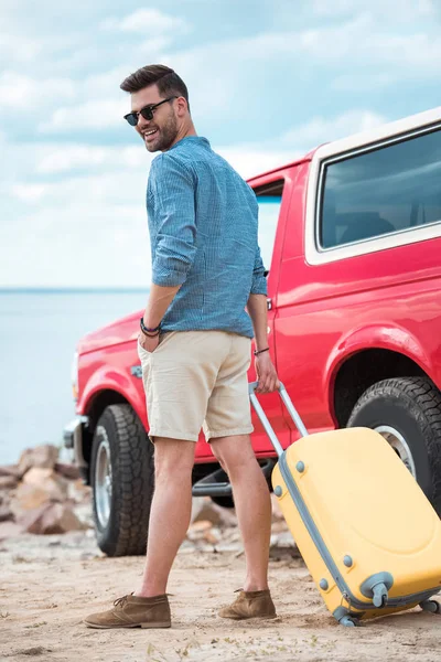 Stilvoller Mann mit Reisetasche fährt zu rotem Jeep am Meer — Stockfoto