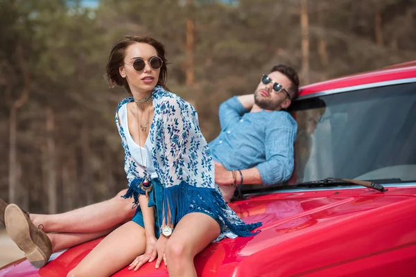 Couple de voyageurs se détendre ensemble sur la voiture rouge — Photo de stock