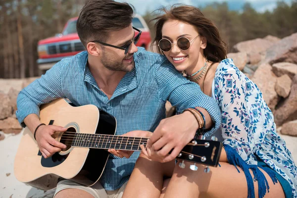Happy couple hugging while man playing acoustic guitar — Stock Photo
