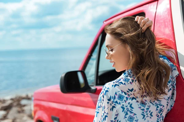 Hermosa mujer con estilo en el coche durante el viaje por carretera cerca del mar - foto de stock