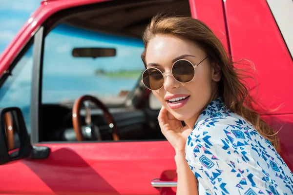 Attraente giovane donna in occhiali da sole vicino auto rossa — Foto stock