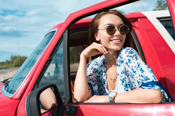 Улыбающаяся молодая женщина в солнечных очках в машине во время поездки — стоковое фото
