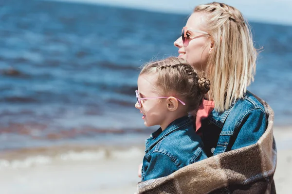 Stylish mother and kid in sunglasses looking at the sea — Stock Photo