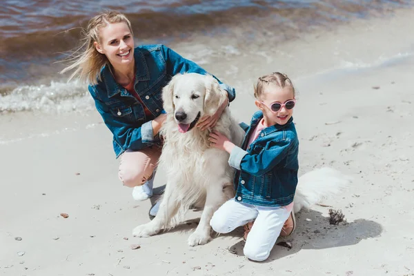 Família feliz com cão retriever dourado na costa do mar — Fotografia de Stock