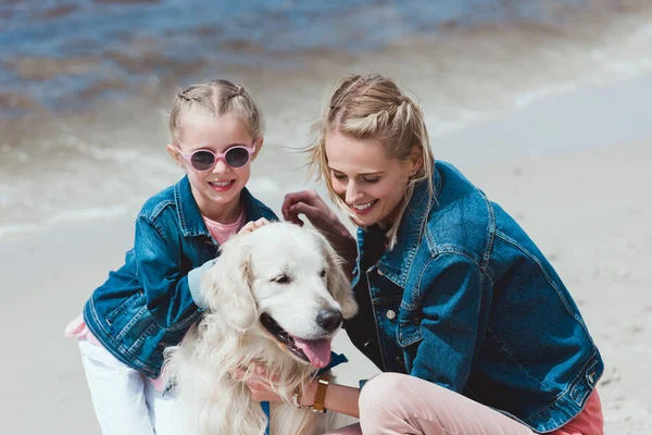 Smiling family with golden retriever dog on sea shore — Stock Photo