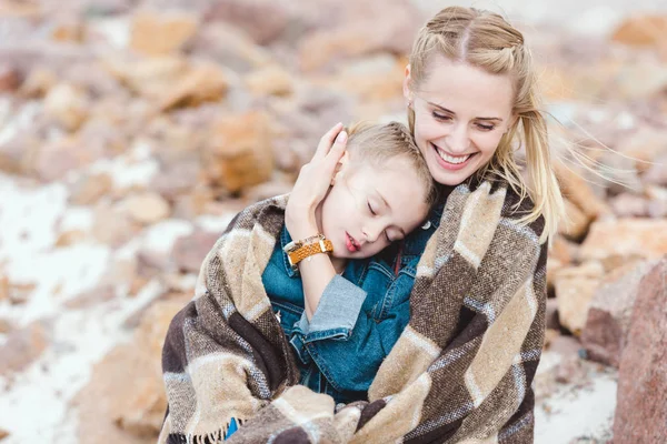 Mère souriante étreignant sa fille endormie adorable dans la couverture — Photo de stock