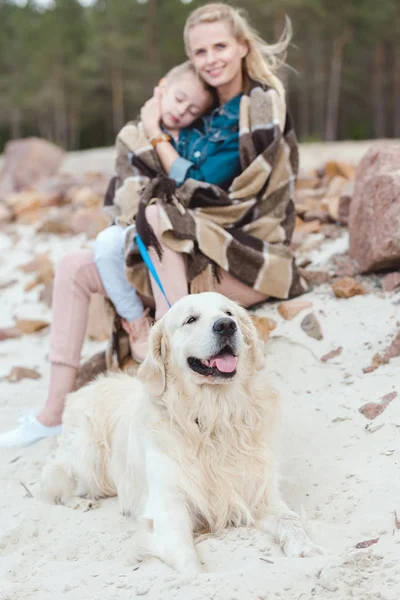 Selective focus of mother and sleeping daughter with golden retriever dog on shore — Stock Photo