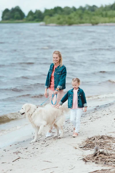 Familia con perro golden retriever en paseo cerca del mar - foto de stock