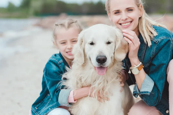 Sonriente madre e hija con golden retriever perro - foto de stock