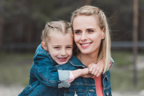 Adorable fille étreignant sa mère souriante — Photo de stock