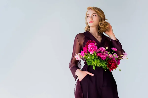 Baixo ângulo de visão da jovem elegante com belas flores olhando para longe isolado em cinza — Fotografia de Stock