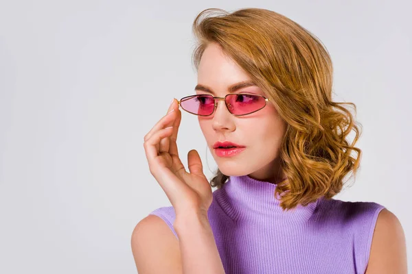 Porträt einer schönen jungen Frau mit pinkfarbener Sonnenbrille, die isoliert auf grau blickt — Stockfoto