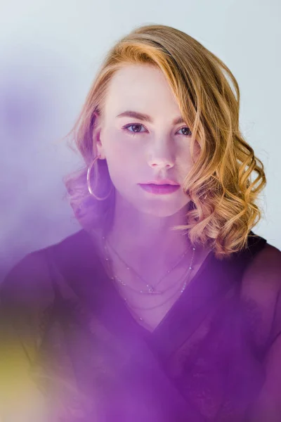 Selective focus of beautiful young woman looking at camera on grey — Stock Photo