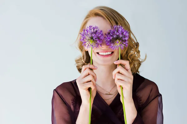Beautiful happy young woman holding bright purple flowers isolated on grey — Stock Photo