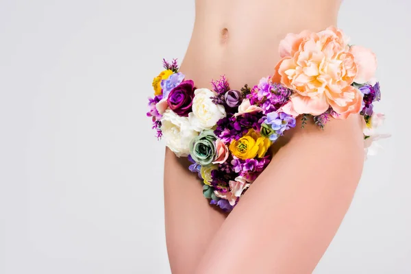 Recortado disparo de chica en bragas hechas de hermosas flores tiernas aisladas en gris - foto de stock