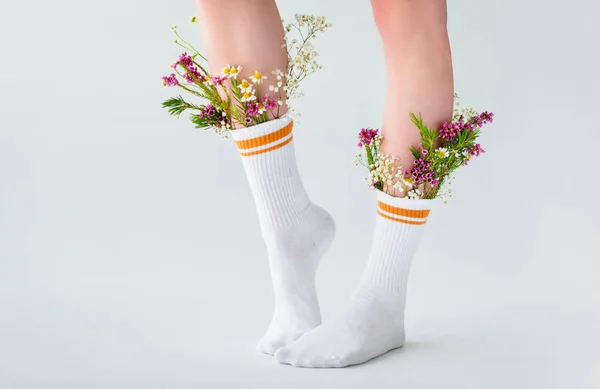 Schnappschuss einer jungen Frau in Socken mit schönen frischen Blumen isoliert auf grau — Stockfoto