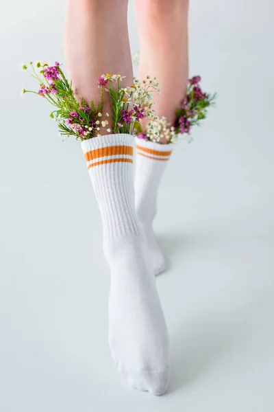 Abgeschnittene Aufnahme von Mädchen in Socken mit schönen Blumen, die isoliert auf grau gehen — Stockfoto