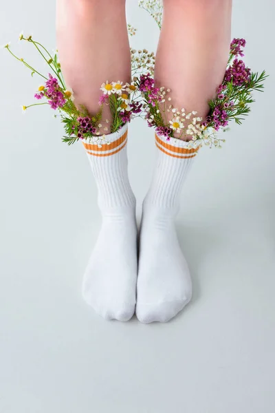 Gros plan vue partielle des jambes féminines en chaussettes avec de belles fleurs isolées sur gris — Photo de stock