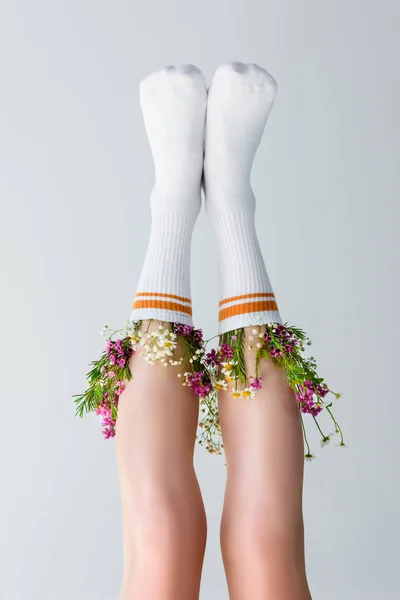 Close-up vista das pernas femininas com flores frescas em meias isoladas em cinza, de cabeça para baixo vista — Fotografia de Stock