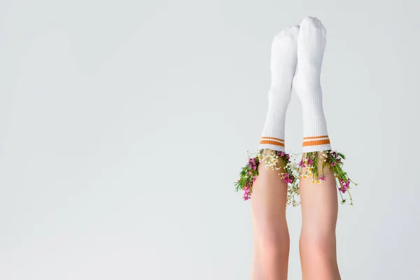 Vista de cabeça para baixo das pernas femininas com flores frescas em meias isoladas em cinza — Fotografia de Stock