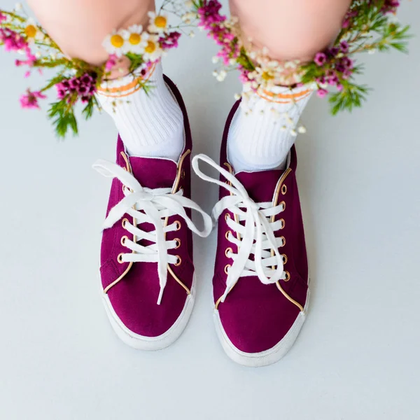 Olhando para baixo vista de pernas femininas com flores frescas em meias isoladas em cinza — Fotografia de Stock