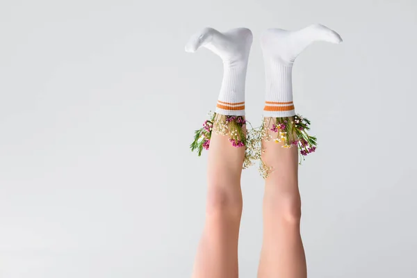 Vista a testa in giù di gambe femminili con fiori in calzini isolati su grigio — Foto stock