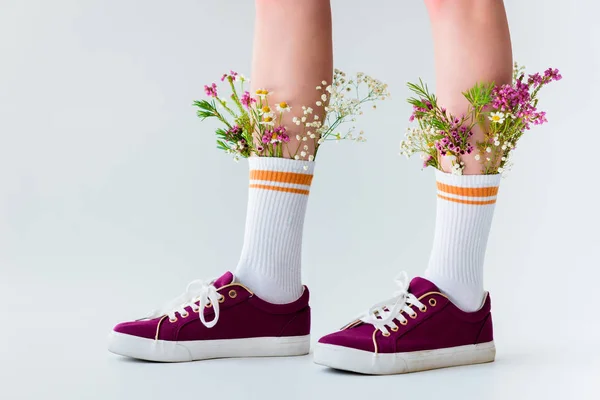 Gros plan vue partielle des jambes féminines avec de belles fleurs en chaussettes isolées sur gris — Photo de stock