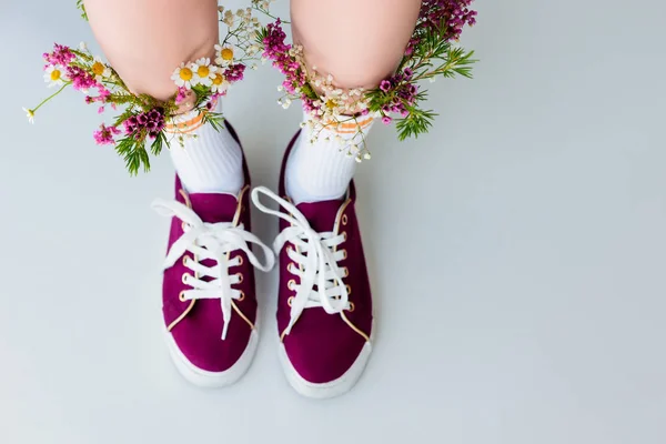 Частичный вид сверху женских ног с цветами в носках, изолированных на сером — стоковое фото