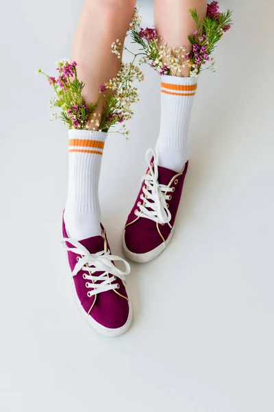 Cropped shot of girl with beautiful flowers in socks isolated on grey — Stock Photo