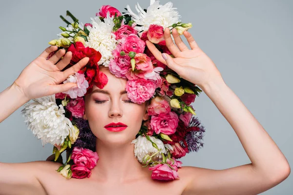 Beautiful young naked woman with closed eyes posing with flowers on head isolated on grey — Stock Photo