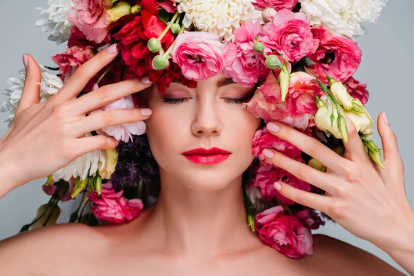 Retrato de linda jovem mulher com olhos fechados posando com belas flores na cabeça isolado em cinza — Fotografia de Stock